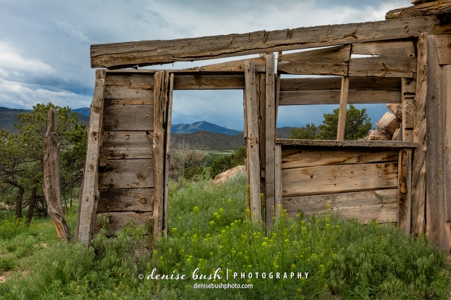 A portion of an Old West settlement acts as a frame for the ominous sky and mountain beyond.